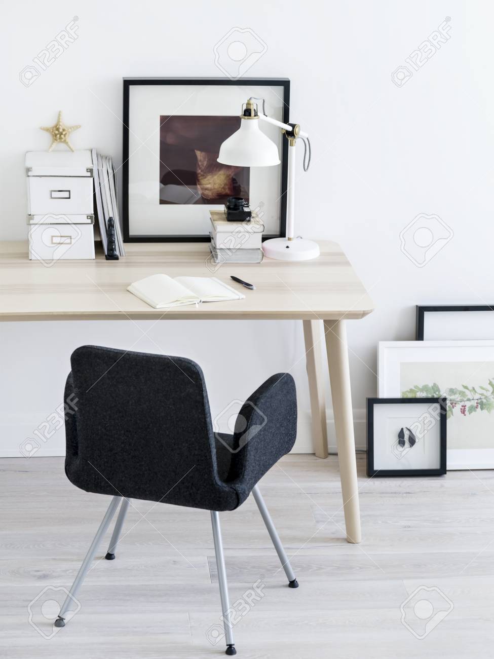 Comfortable chair standing near small table and nice frames pictures in stylish room stock photo