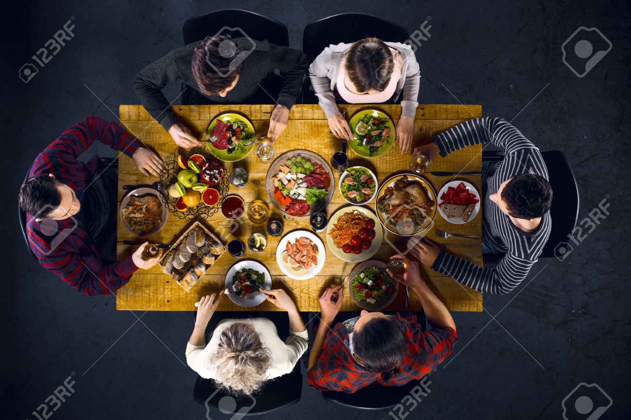 Top view creative photo of friends sitting at wooden vintage table. Friends of six having dinner. They with plates full of delicious meal and glasses with drinks - 54207294 Top view creative photo of friends sitting at wooden vintage table. Friends of six having dinner. They with plates full of delicious meal and glasses with drinks - 54207294