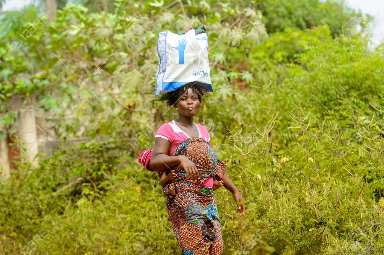 Ouidah Benin 10 Janvier 17 Femme Beninoise Non Identifiee Porte Un Bebe Sur Le Dos Et Un Sac En Plastique Sur La Tete Les Beninois Souffrent De La Pauvrete En