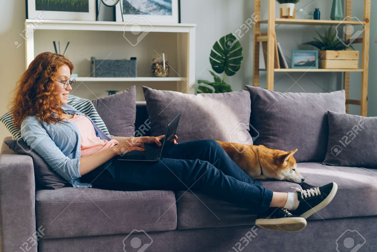 Happy Student Pretty Girl Is Using Laptop Sitting On Couch With