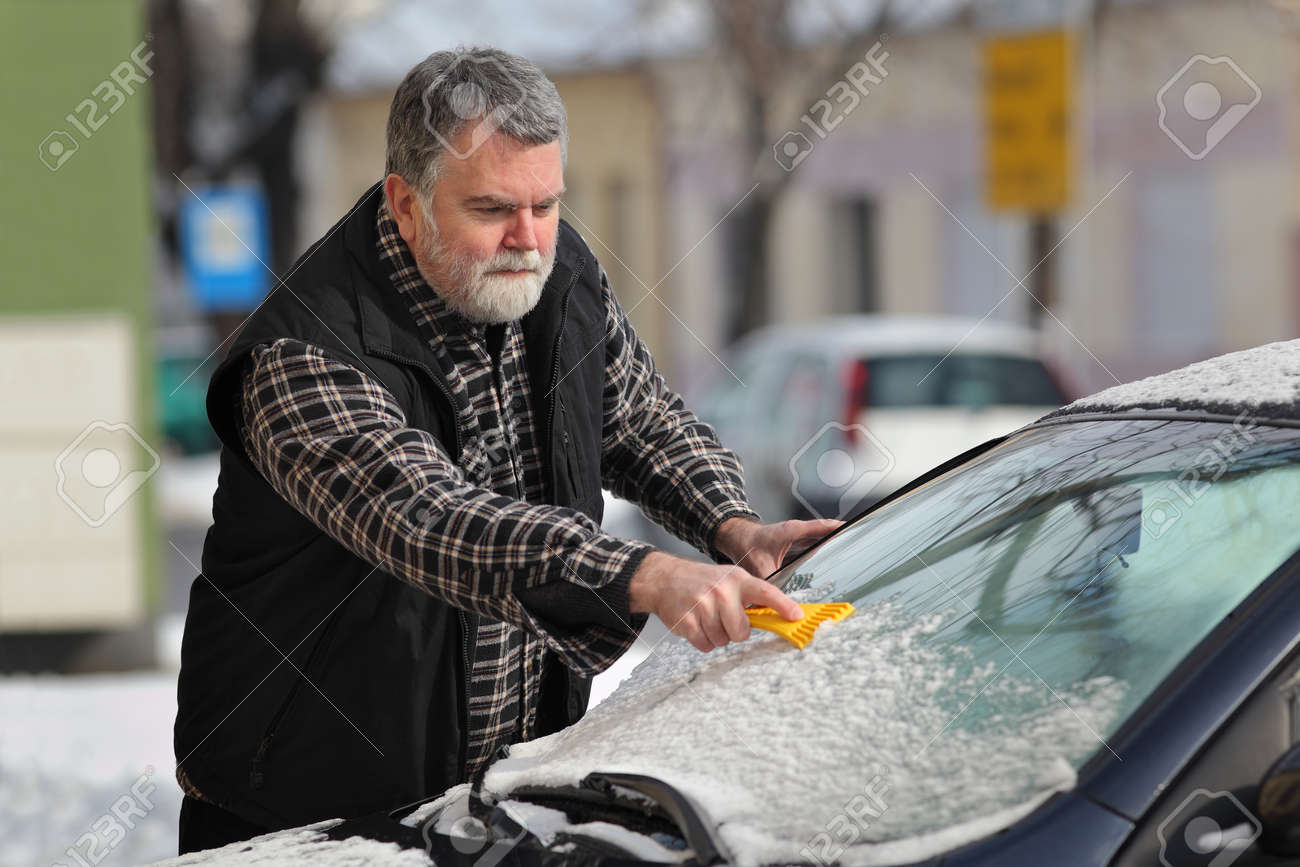 スクレーパーを使用してフロントガラスog車から雪を洗浄するドライバー の写真素材 画像素材 Image