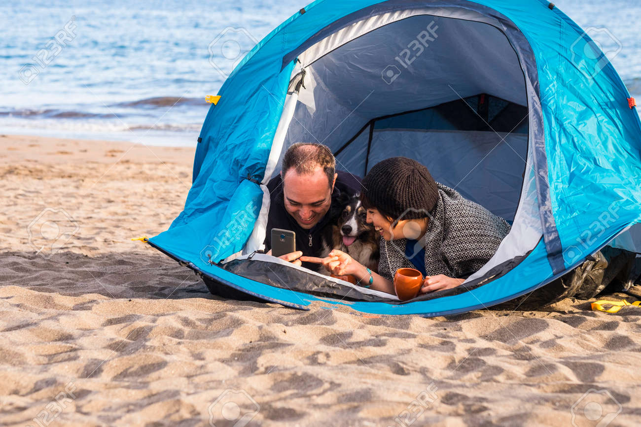 Couple Looking At The Smart Phone And Have Fun Inside A Tent
