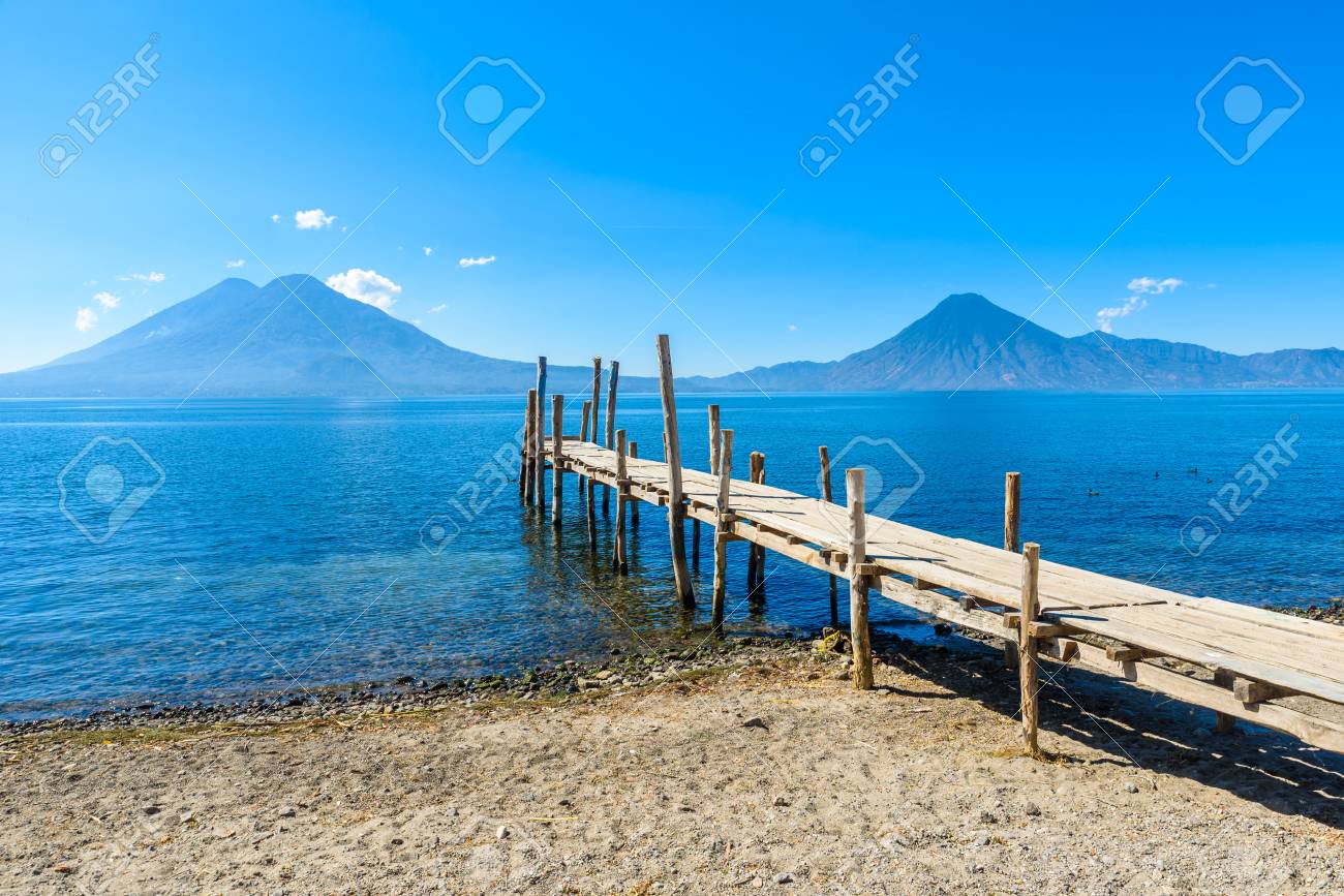 Wooden pier at Lake Atitlan on the beach in Panajachel, Guatemala. With beautiful landscape scenery of volcanoes Toliman, Atitlan and San Pedro in the background. - 91169879 Wooden pier at Lake Atitlan on the beach in Panajachel, Guatemala. With beautiful landscape scenery of volcanoes Toliman, Atitlan and San Pedro in the background. - 91169879