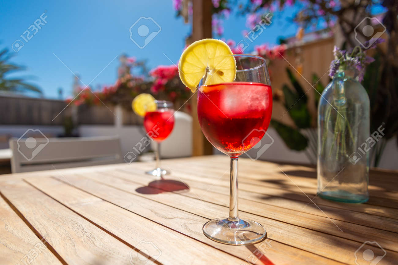 Refreshing Tropical Cocktail Drink on a table in the garden - 143208184 Refreshing Tropical Cocktail Drink on a table in the garden - 143208184
