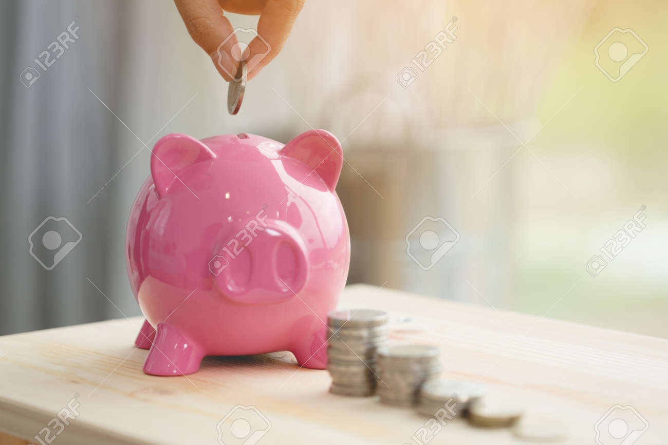 Little hand saving money in pink piggy bank - 105548652 Little hand saving money in pink piggy bank - 105548652