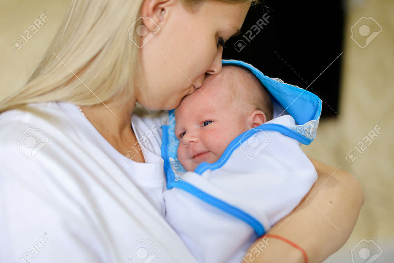 若い女性 Lulls と歌う歌子 優しくハグと子供と話して赤ちゃん泣くし 母を見てある母親の明るいルームで腕白い T シャツ 白い毛布ウィットに包まれた新生児に身を包んだ女性金髪欧州外観 の写真素材 画像素材 Image