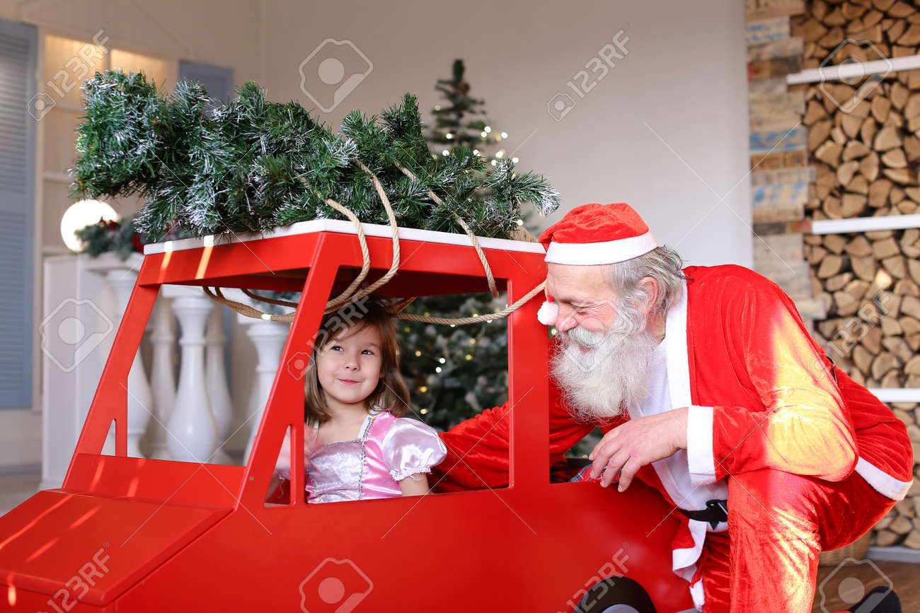 赤い車の男と遊ぶの楽しい女性の子供は赤い衣装に身を包んだ クリスマス装飾の前の家します 冬の休日のための準備の概念 の写真素材 画像素材 Image