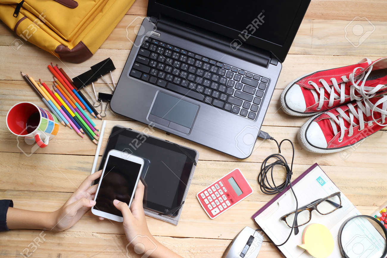 Close up hands holding big smart phone while connecting to wireless, businessman using technology sitting at modern loft wooden desk, people and modern devices everywhere - 42541108 Close up hands holding big smart phone while connecting to wireless, businessman using technology sitting at modern loft wooden desk, people and modern devices everywhere - 42541108