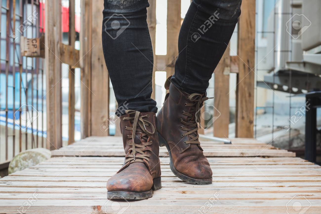 Hombre Joven De Moda Usar Una Camisa Negro, Vaqueros Negros Y Botas De Cuero Marrón En El Suelo. Botas Cuero Viejos. Fotos, Retratos, Imágenes Y Fotografía De Archivo Libres De
