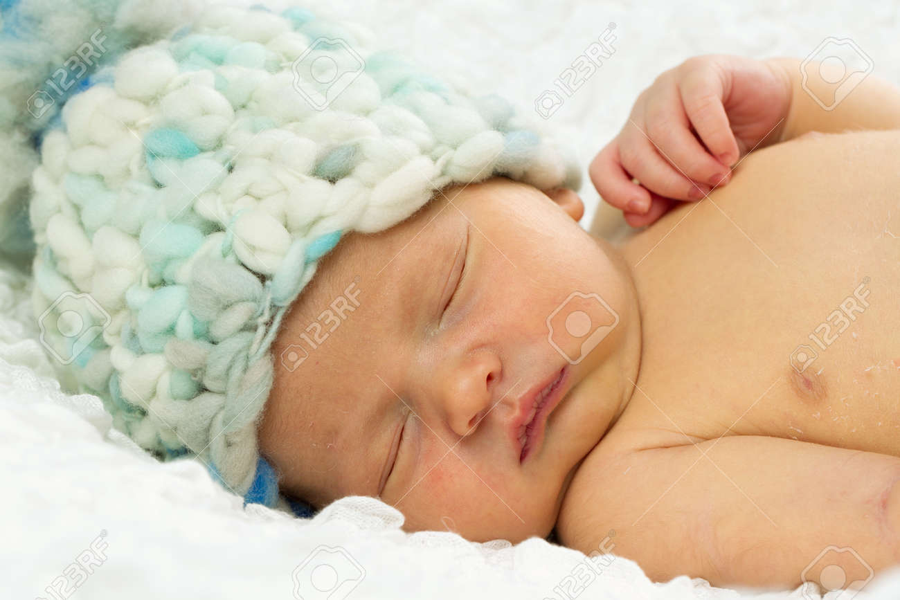 新生児男の赤ちゃん睡眠中に彼の頭に帽子を身に着けています の写真素材 画像素材 Image