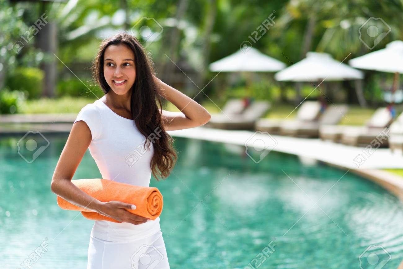 幸せな笑顔に戻って彼女の下で巻きタオルで輝く青いプールの前にリゾート ホテルで熱帯の夏の休暇立って魅力的なアジアの女性を探してください の写真素材 画像素材 Image