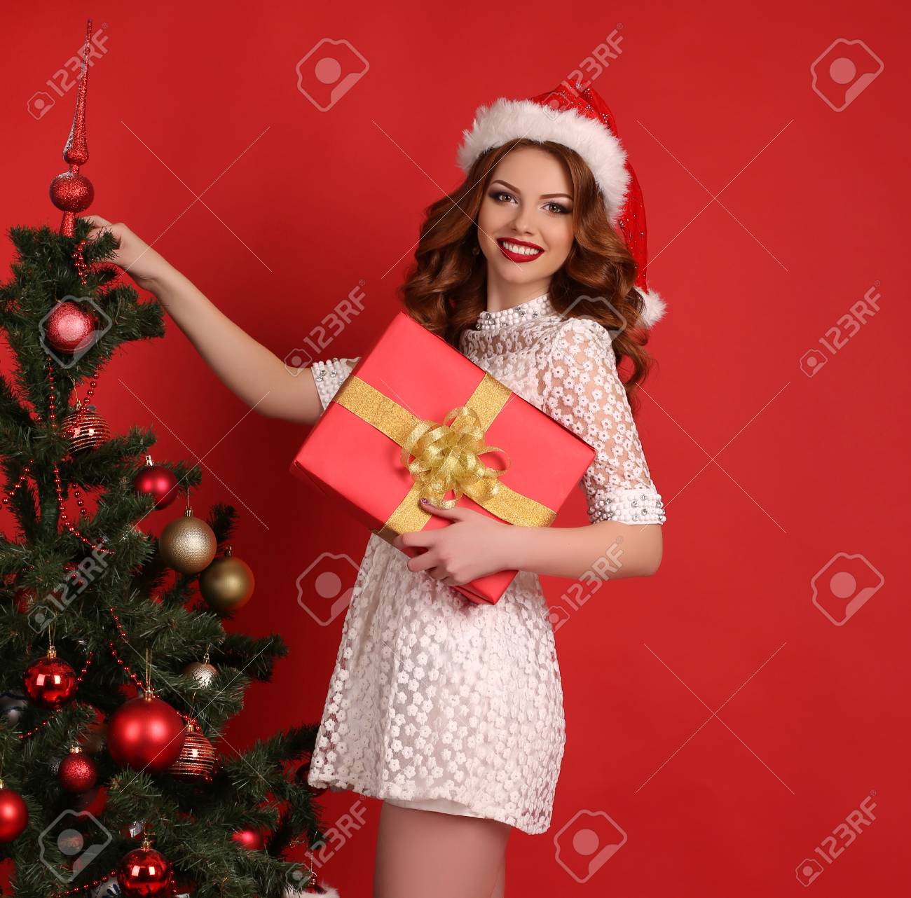 黒い髪と大きなクリスマス プレゼント エレガントなドレスで 明るいメイクで美しい若い女の子のファッション スタジオ写真の横にポーズ ツリーを装飾 の写真素材 画像素材 Image