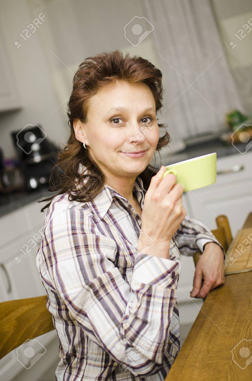 A woman is drinking coffee in the kitchen. - 17079596 A woman is drinking coffee in the kitchen. - 17079596