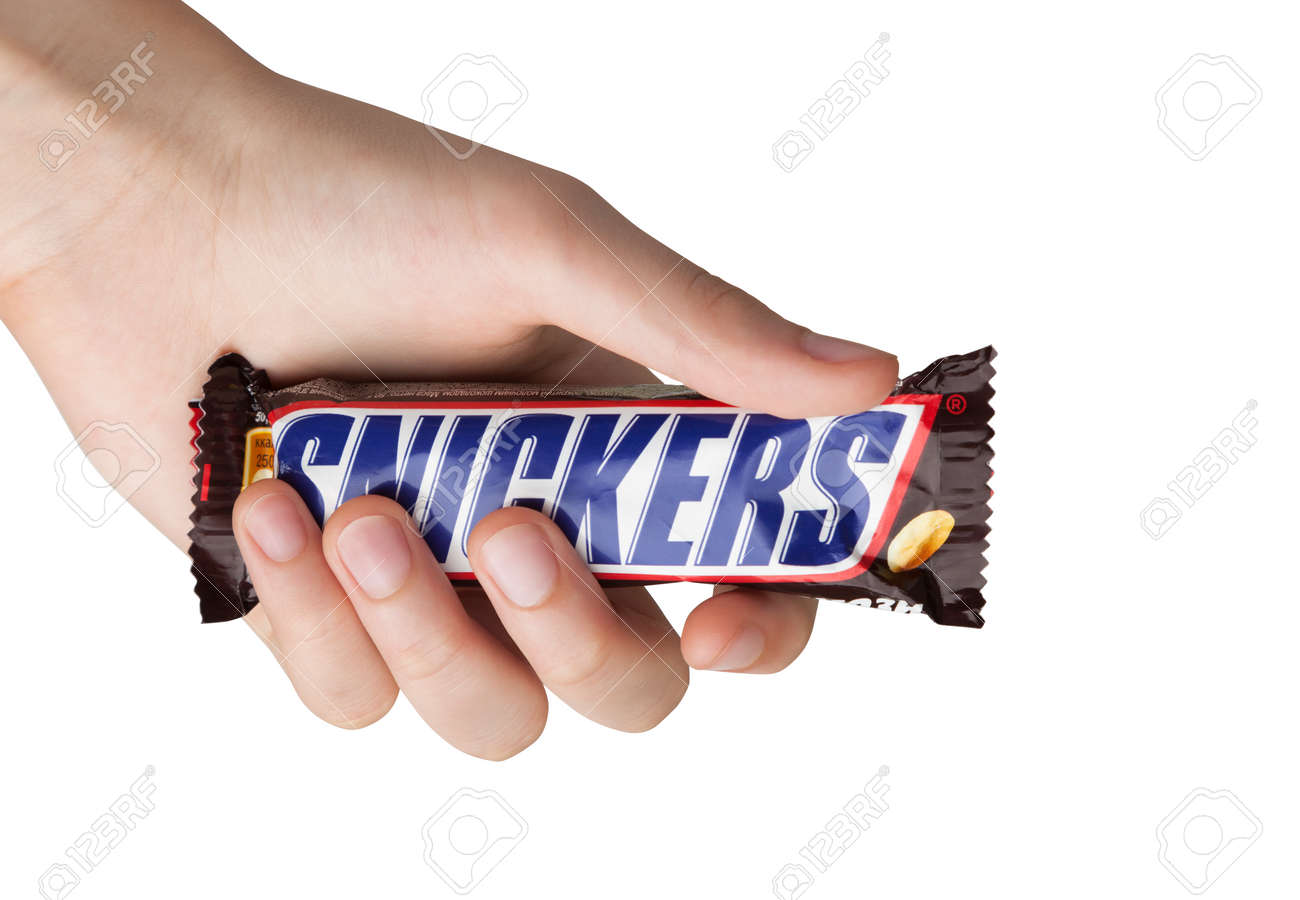 Hand holding a Snickers chocolate bar - 92221818 Hand holding a Snickers chocolate bar - 92221818