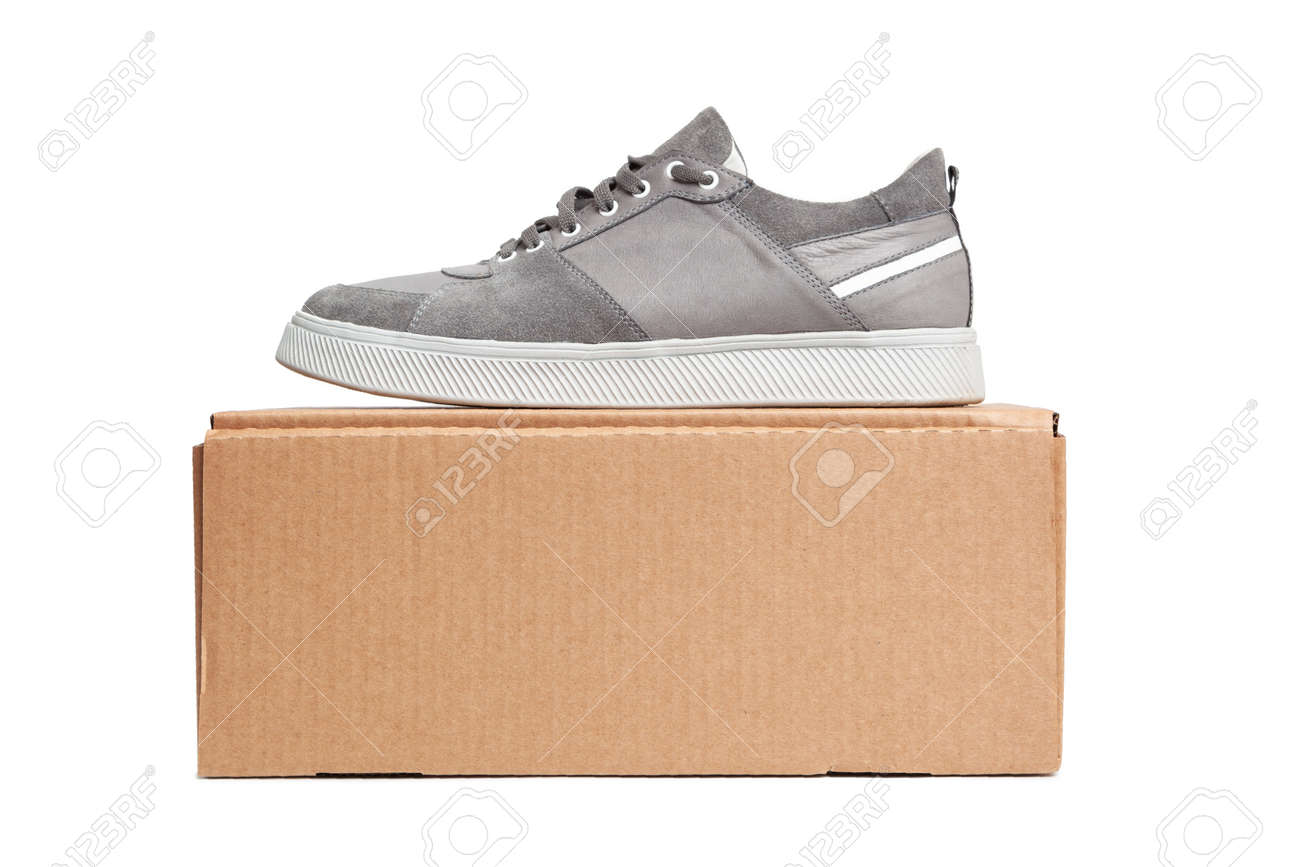 Gray casual sports shoes, sneaker on a brown cardboard box isolated on a white background - 170242763 Gray casual sports shoes, sneaker on a brown cardboard box isolated on a white background - 170242763