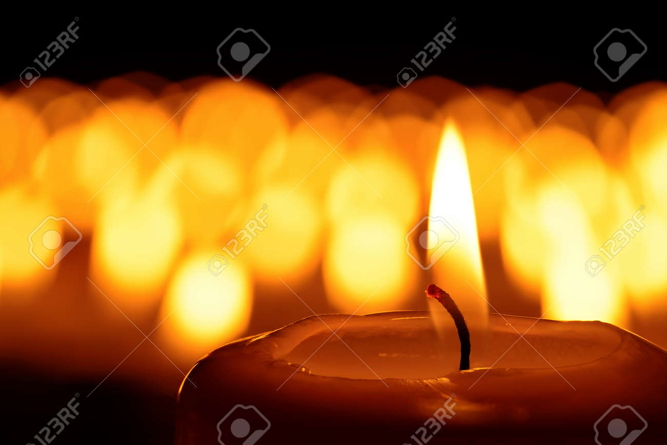 Candle in front of many defocused candleflames creating a spiritual atmosphere and in remembrance of loved ones - 48595530 Candle in front of many defocused candleflames creating a spiritual atmosphere and in remembrance of loved ones - 48595530