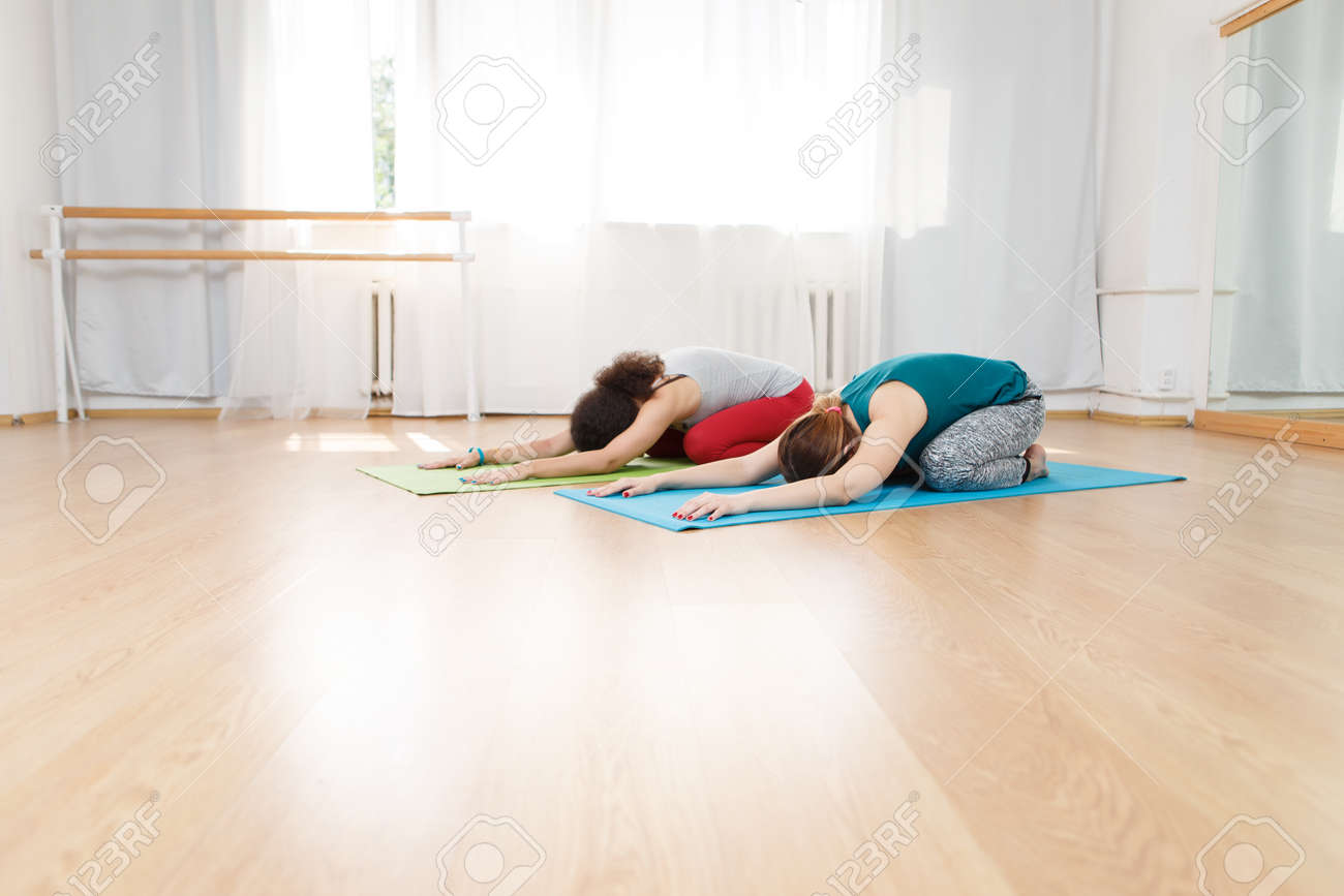 Two Young Caucasian Women Working Out In Yoga Center Asana On