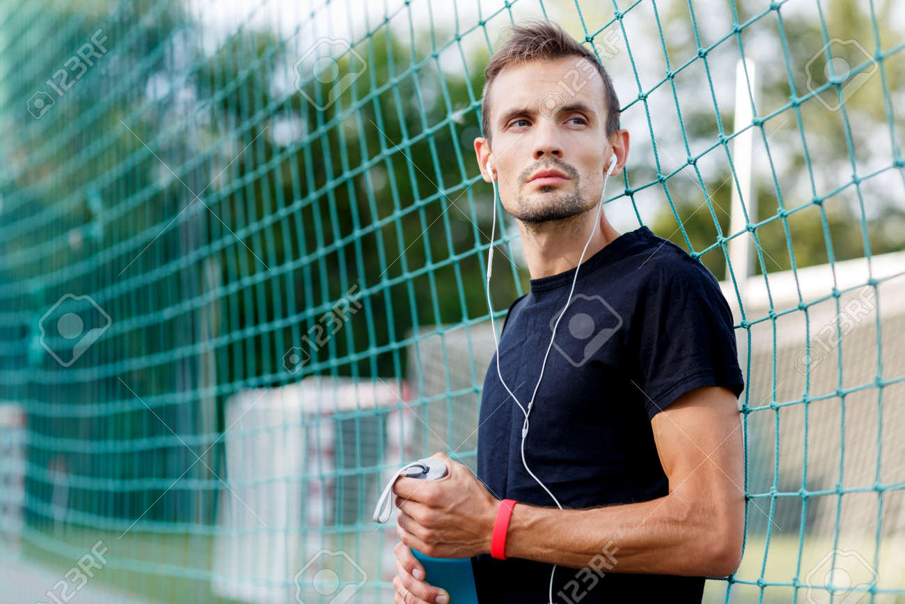 젊은 남자 축구 필드에 물병과 흰색 헤드폰에 맞게 로열티 무료 사진, 그림, 이미지 그리고 스톡포토그래피. Image 66436114
