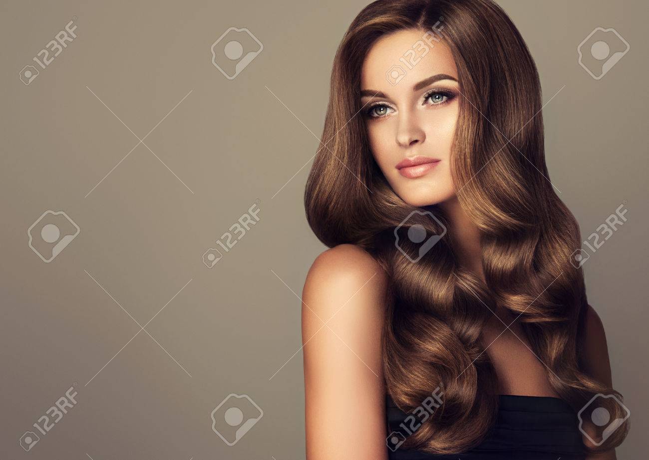 Brunette girl with long and shiny wavy hair . Beautiful model with curly hairstyle . - 62540849 Brunette girl with long and shiny wavy hair . Beautiful model with curly hairstyle . - 62540849