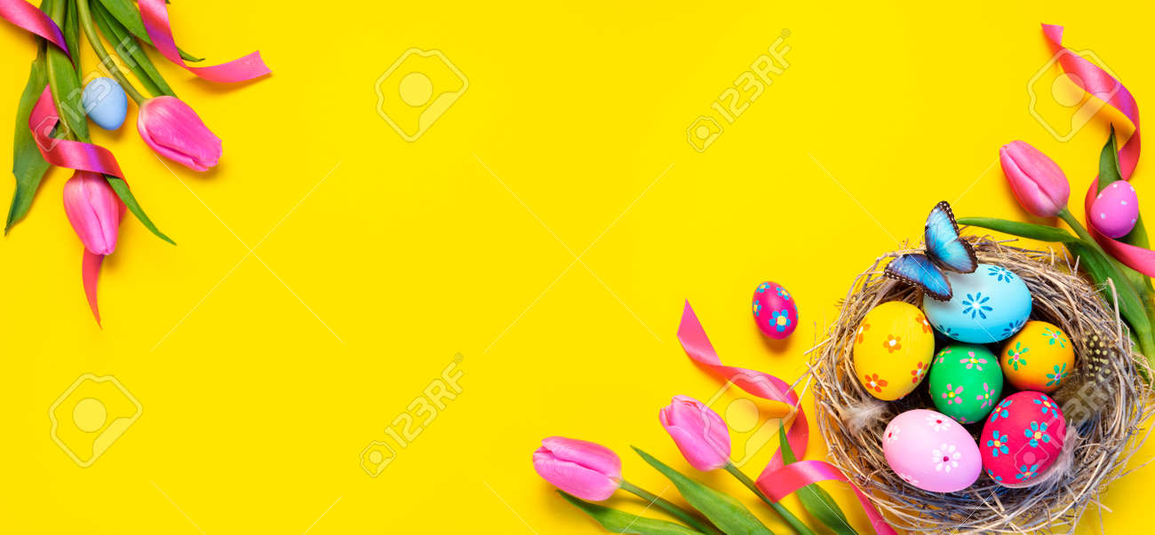 Easter - Colorful Eggs In Nest With Butterfly And Pink Tulips In Yellow Background - 165476402 Easter - Colorful Eggs In Nest With Butterfly And Pink Tulips In Yellow Background - 165476402