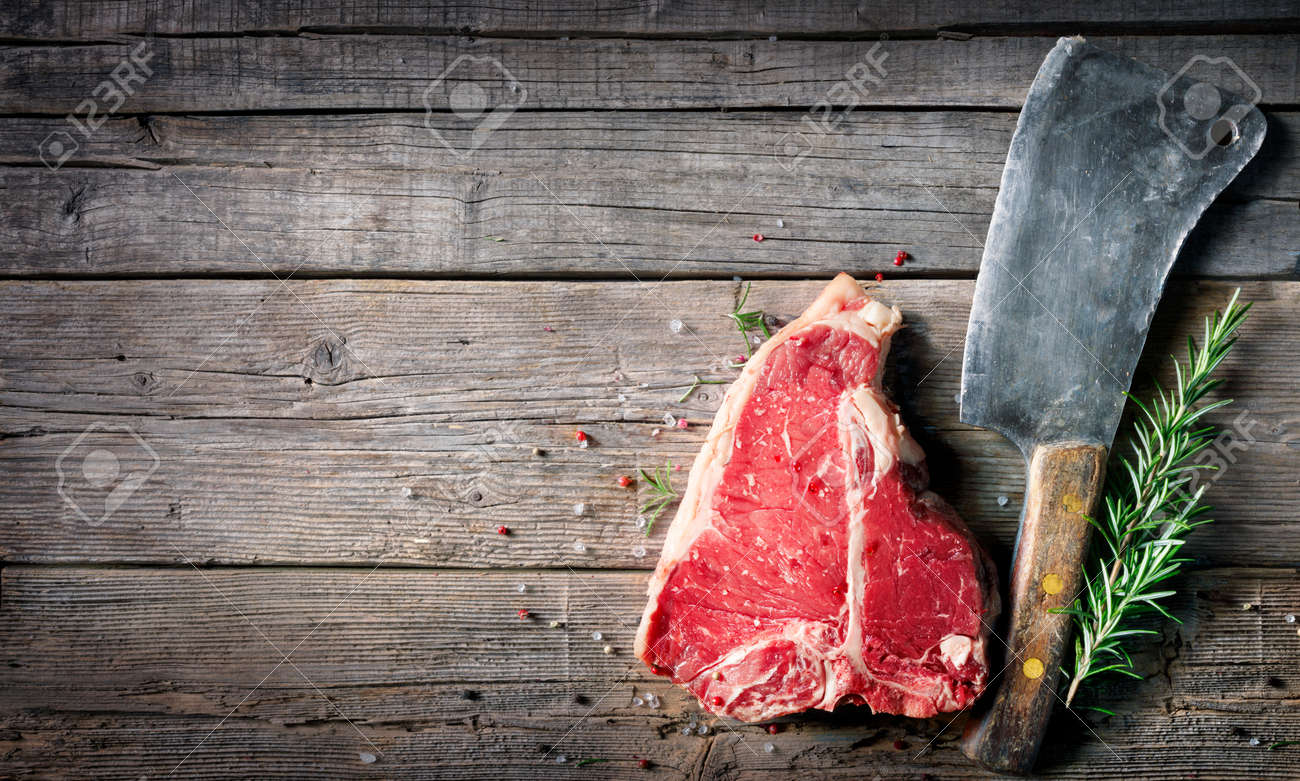 T-bone beef steak - Raw meat for grill with fresh herbs and cleaver - 168103872 T-bone beef steak - Raw meat for grill with fresh herbs and cleaver - 168103872