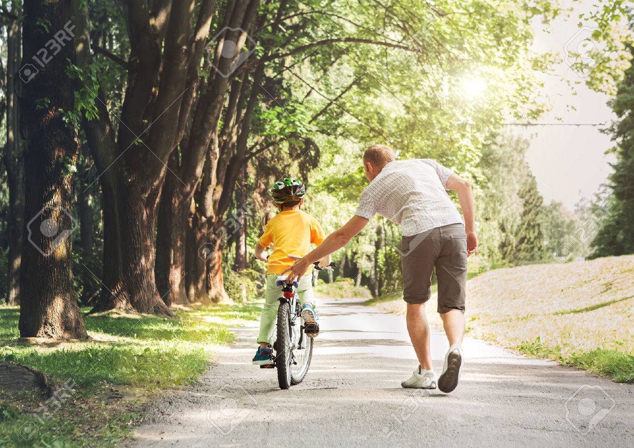 Father help his son ride a bicycle - 54668941 Father help his son ride a bicycle - 54668941