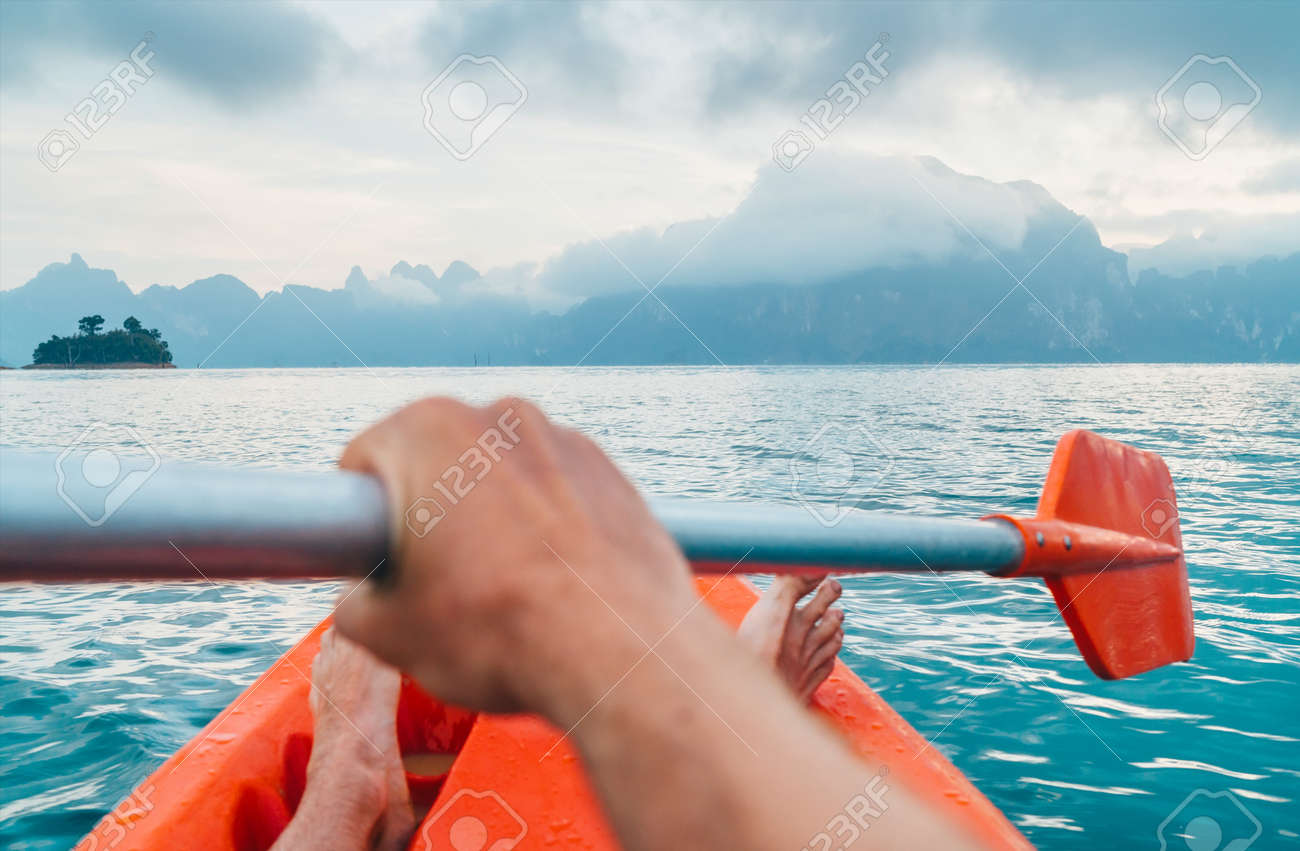 POV of Man floating in kayak holding paddle during early morning tour. Khao Sok national park, Cheow Lan lake, Thailand - 120541936 POV of Man floating in kayak holding paddle during early morning tour. Khao Sok national park, Cheow Lan lake, Thailand - 120541936