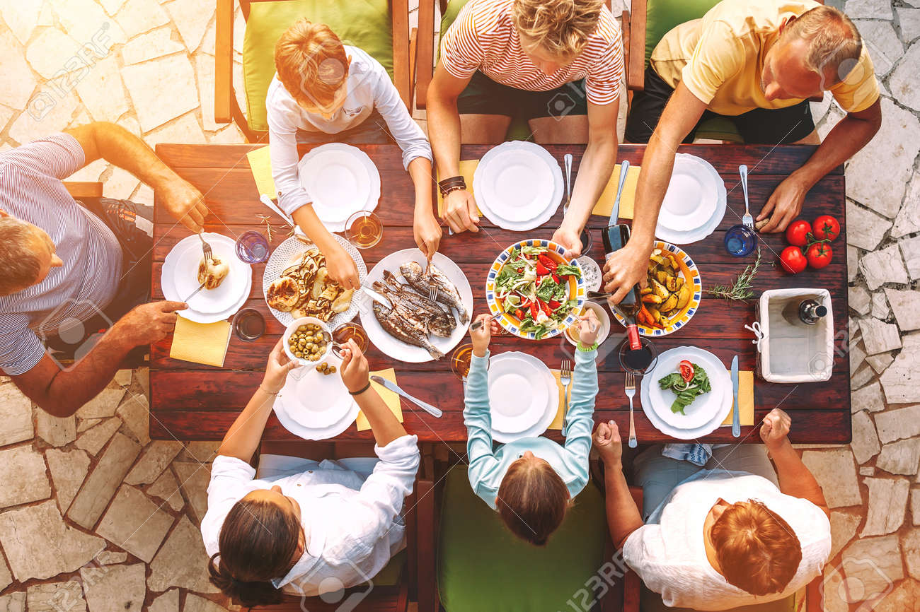 Big family have a dinner with fresh cooked meal on open garden terrace - 121462490 Big family have a dinner with fresh cooked meal on open garden terrace - 121462490