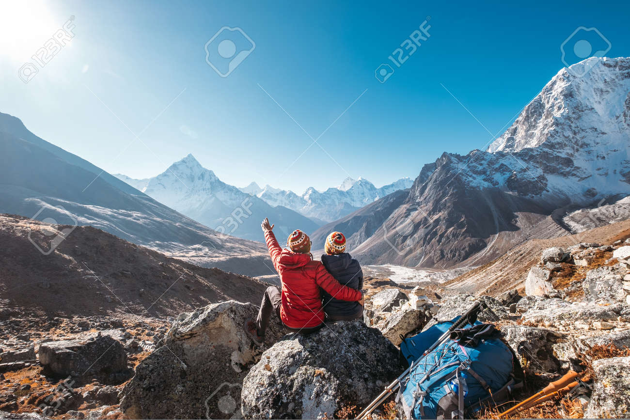 Couple having a rest on Everest Base Camp trekking route near Dughla 4620m. - 134360827 Couple having a rest on Everest Base Camp trekking route near Dughla 4620m. - 134360827