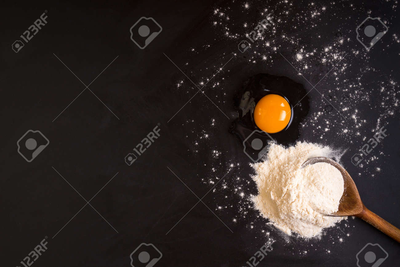 Rustic Wooden Spoon With A Flour A Raw Egg On A Black Chalkboard