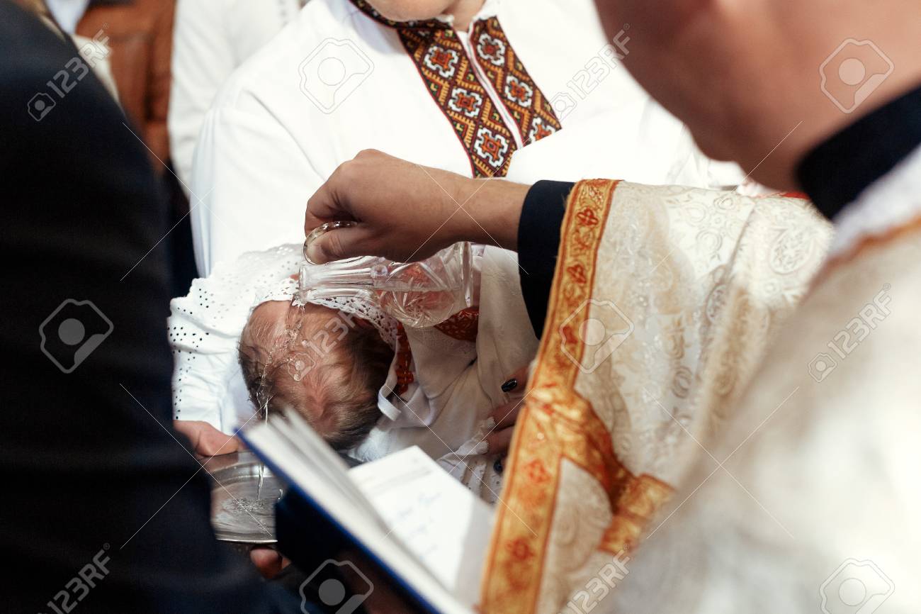 baptism baby with holy water pouring on head at christening stock