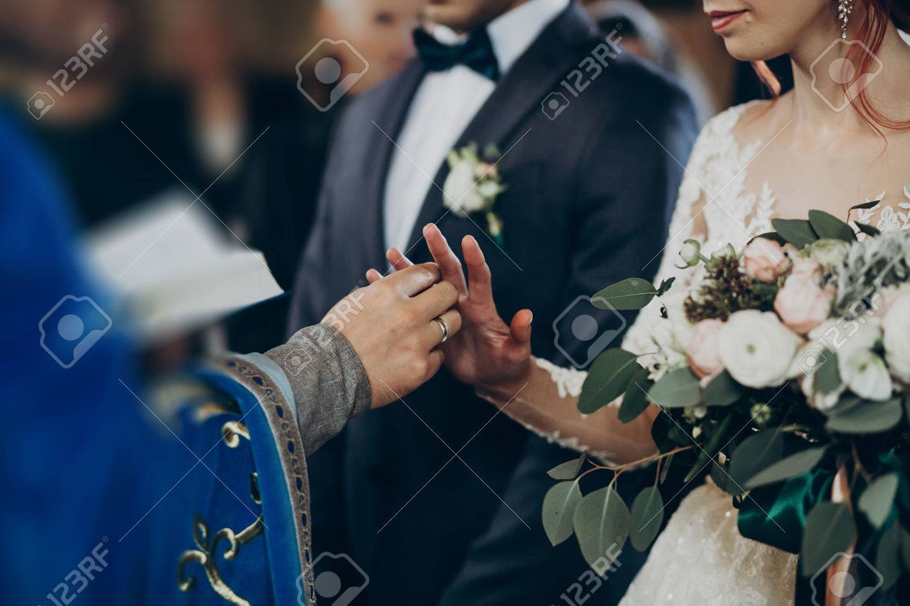 Pareja De Poniendo Anillos De Boda En El Matrimonio La Iglesia. Elegantes Novios E Intercambiando Anillos. Momento Emocional, Espacio Para El Texto. Concepto De Religion Fotos, Retratos, Imágenes Y