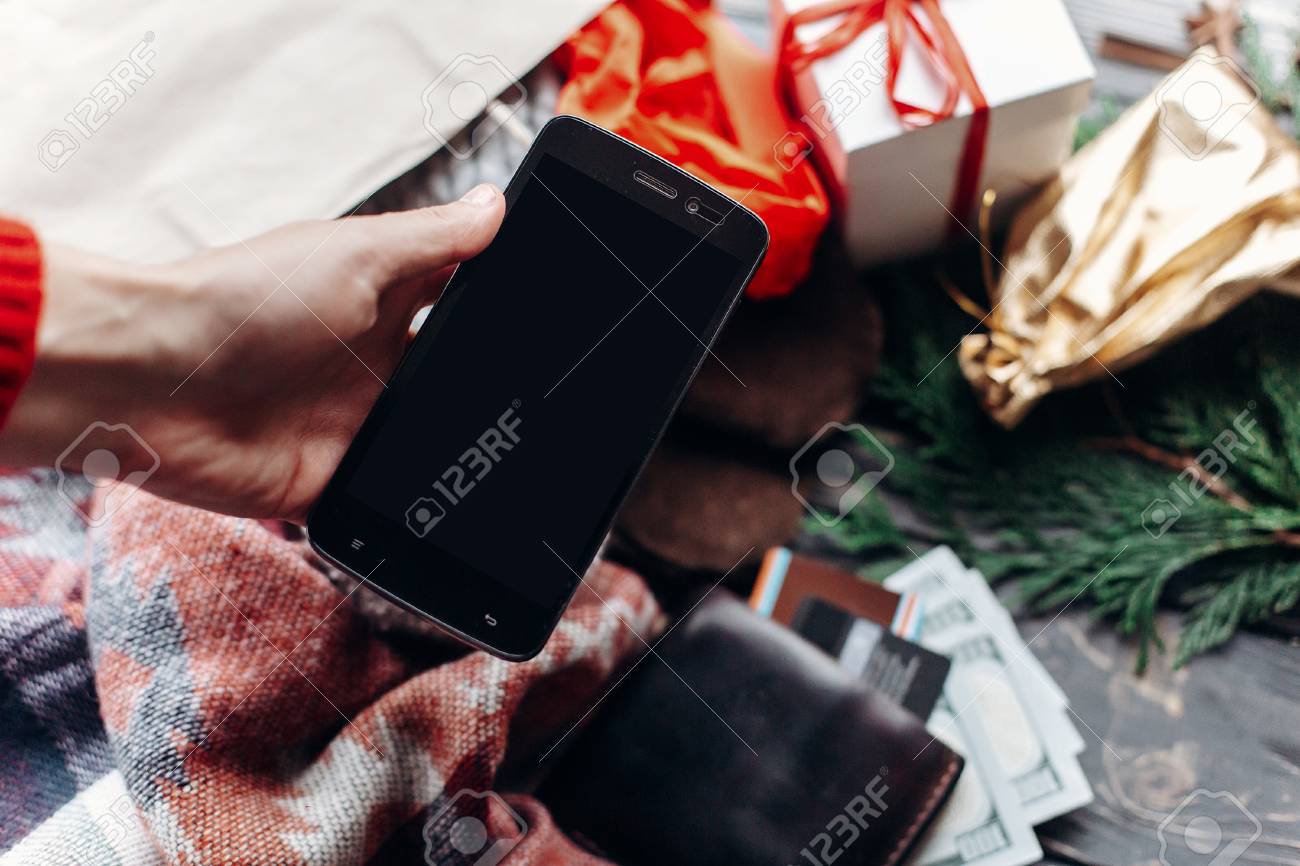 クリスマス ショッピングのコンセプトです 空の画面で携帯電話を持つ手 季節限定販売 素朴な背景に財布 プレゼントの袋 テキストのためのスペースと広告 アプリ の写真素材 画像素材 Image 82445949