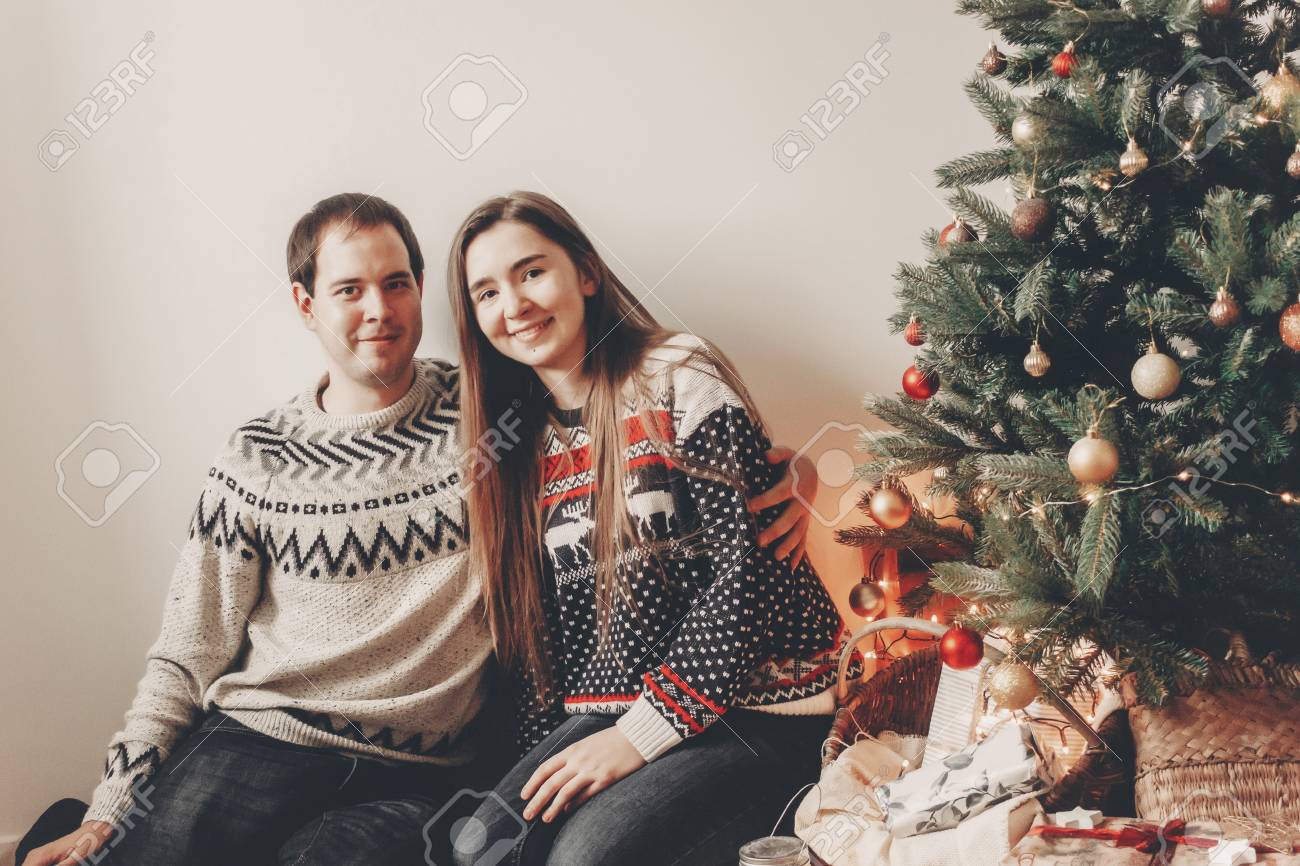 ハグ 居心地の良い夜の部屋でクリスマス ツリーで笑顔のセーターで