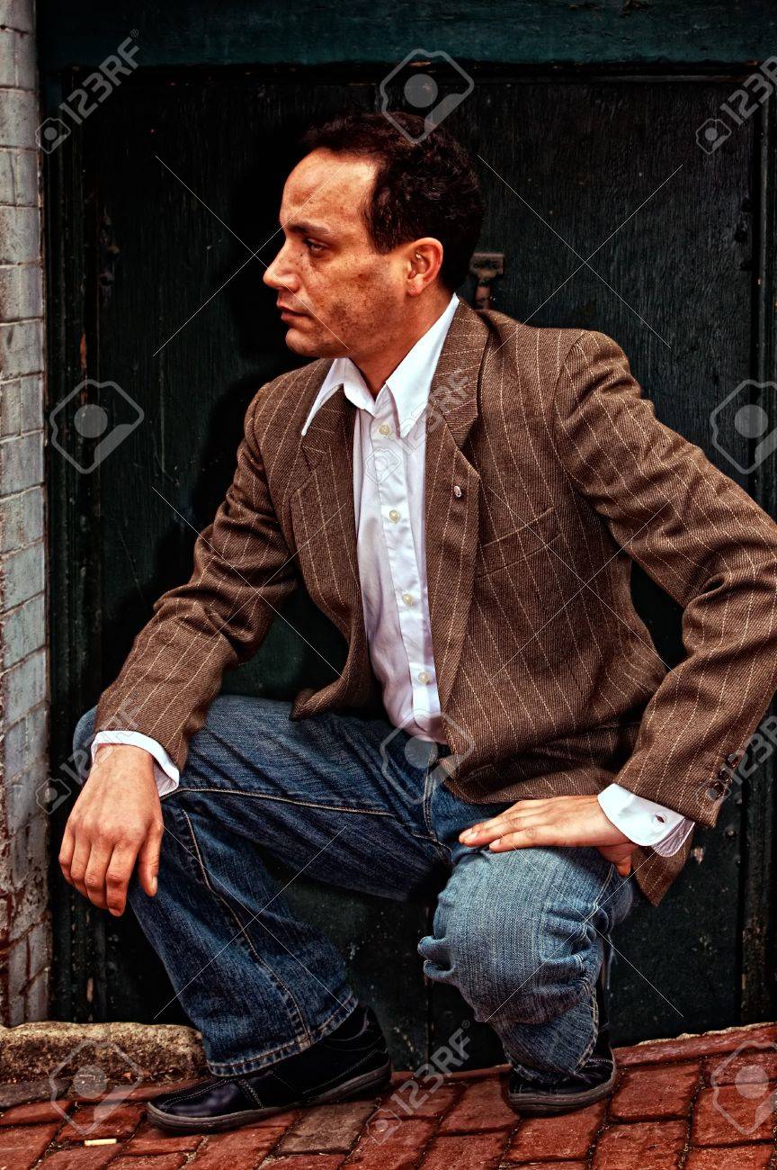 マサチューセッツ州のボストンで煉瓦歩道に通りを探しているスーツのジャケット ワイシャツ ブルー ジーンズを着ての戸口の前にしゃがむ民族のアメリカ人男性 の写真素材 画像素材 Image