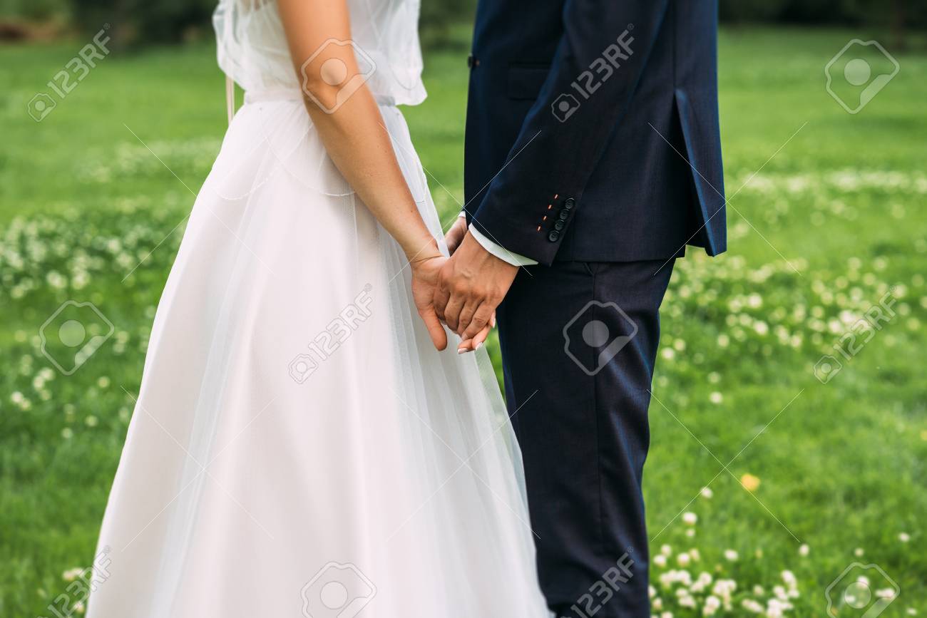 Hands of bride and groom. New young couple holding hands after their wedding. Young married couple holding hands, ceremony wedding day. Closeup view of married couple holding hands - 125107828 Hands of bride and groom. New young couple holding hands after their wedding. Young married couple holding hands, ceremony wedding day. Closeup view of married couple holding hands - 125107828