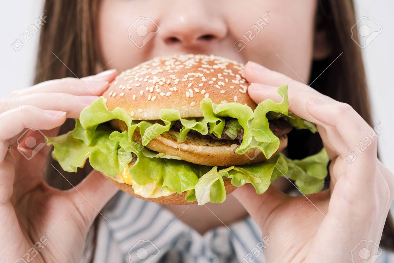Young Beautiful Brunette Girl On A White Background With A Hamburger In Her  Hands. Eating With Pleasure Fast Food. Close-up Face And Hands. Stock  Photo, Picture and Royalty Free Image. Image 117467305., image size:1300x866