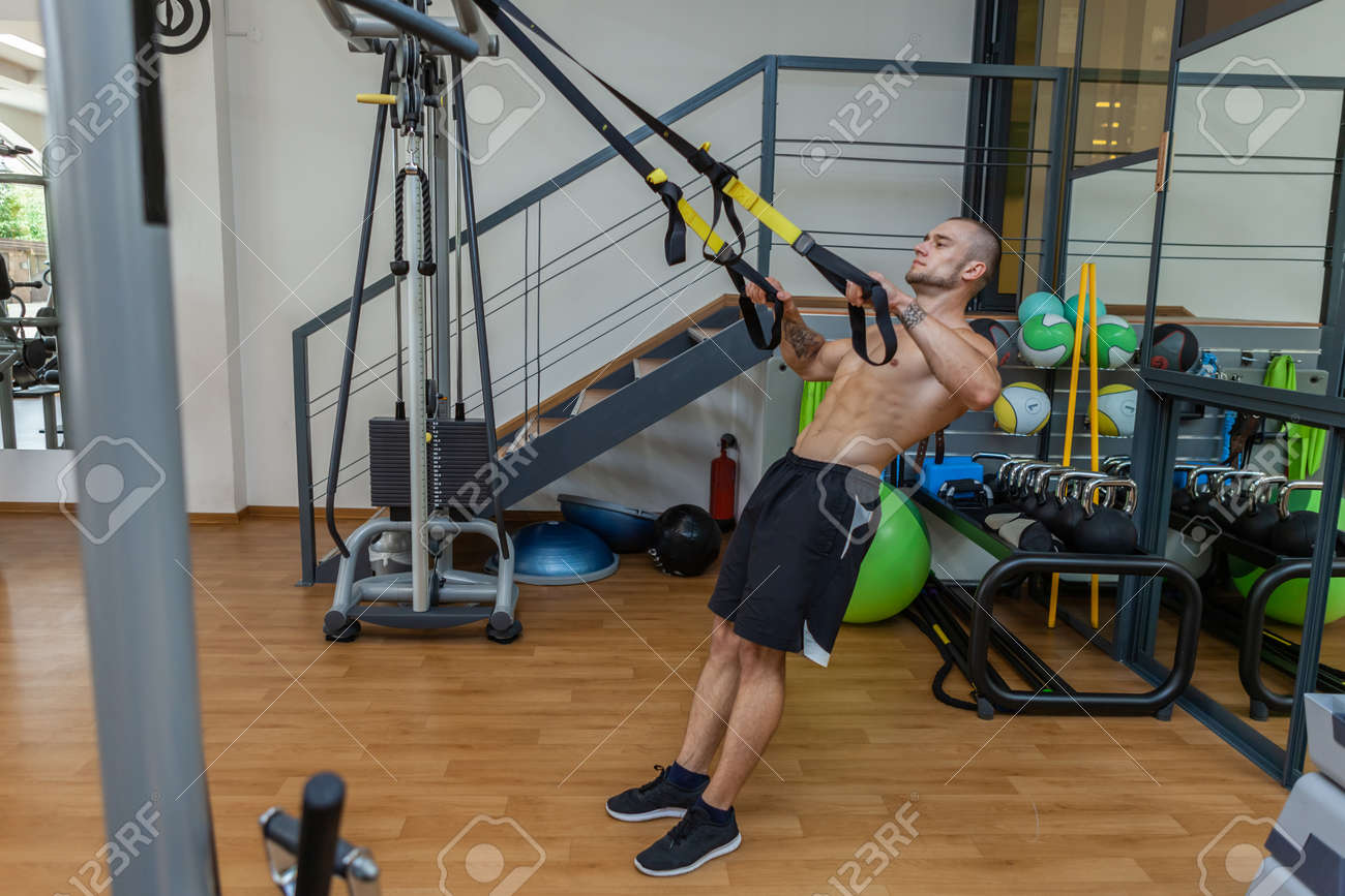 서스펜션 스트랩으로 근육을 운동하는 체육관 보디빌더의 피트니스 Trx 시스템을 갖춘 근육질의 몸통 남자 훈련 로열티 무료 사진, 그림,  이미지 그리고 스톡포토그래피. Image 186506550
