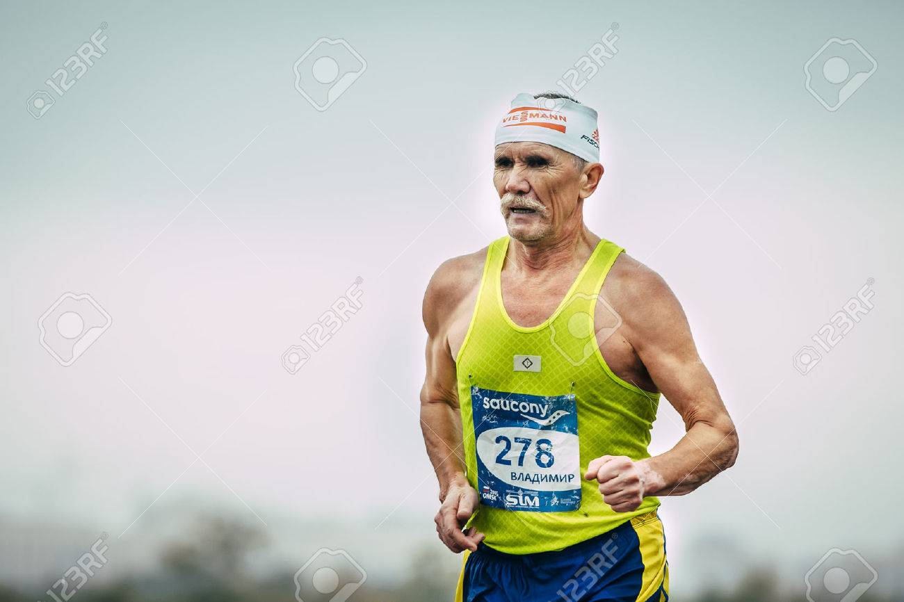 Omsk, Russia - September 20, 2015: elderly male runner running during Siberian international marathon. background of sky - 45849527 Omsk, Russia - September 20, 2015: elderly male runner running during Siberian international marathon. background of sky - 45849527