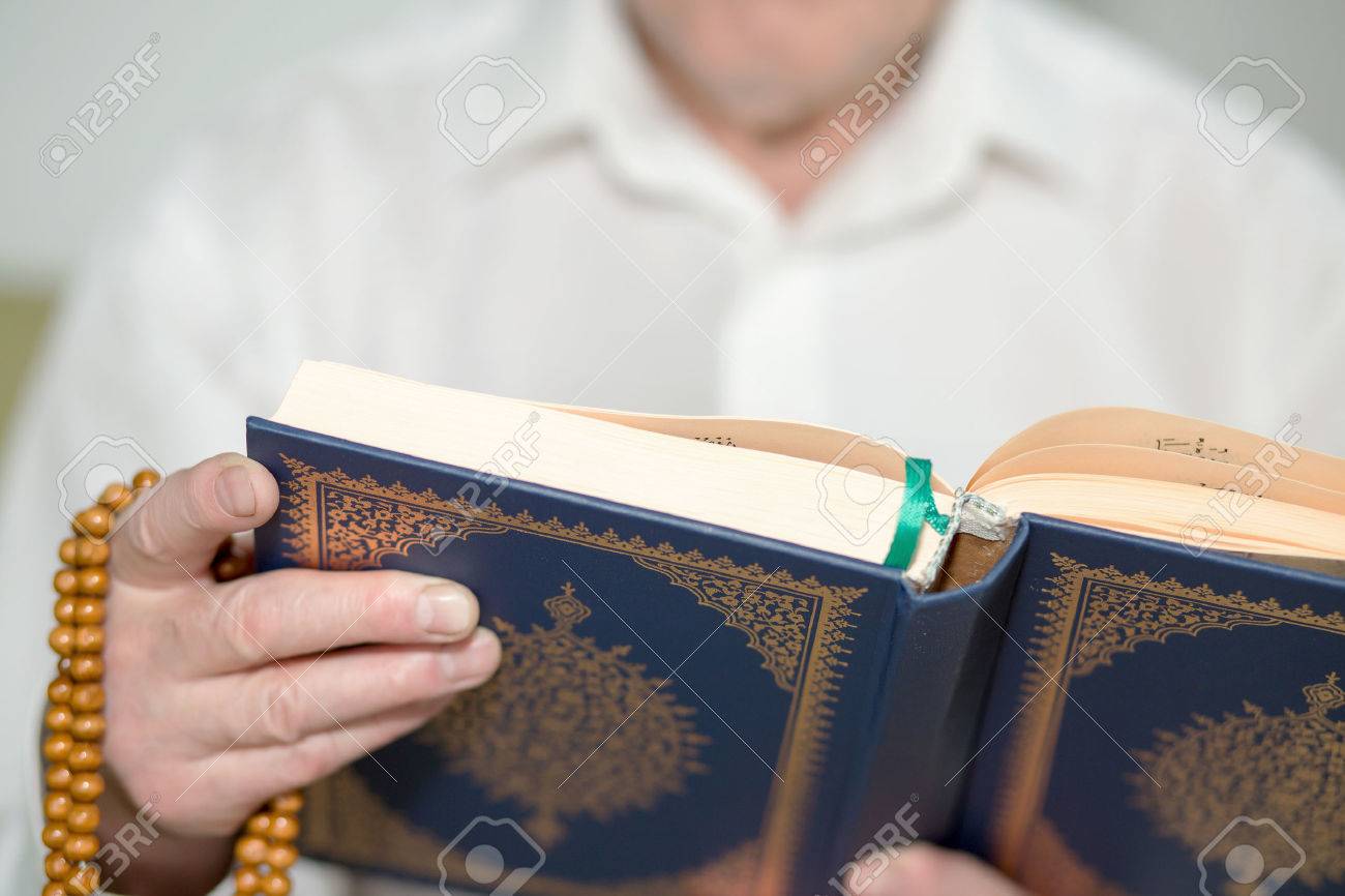 An old man's hand with rosary beads holding the Koran. Selective focus - 46041806 An old man's hand with rosary beads holding the Koran. Selective focus - 46041806