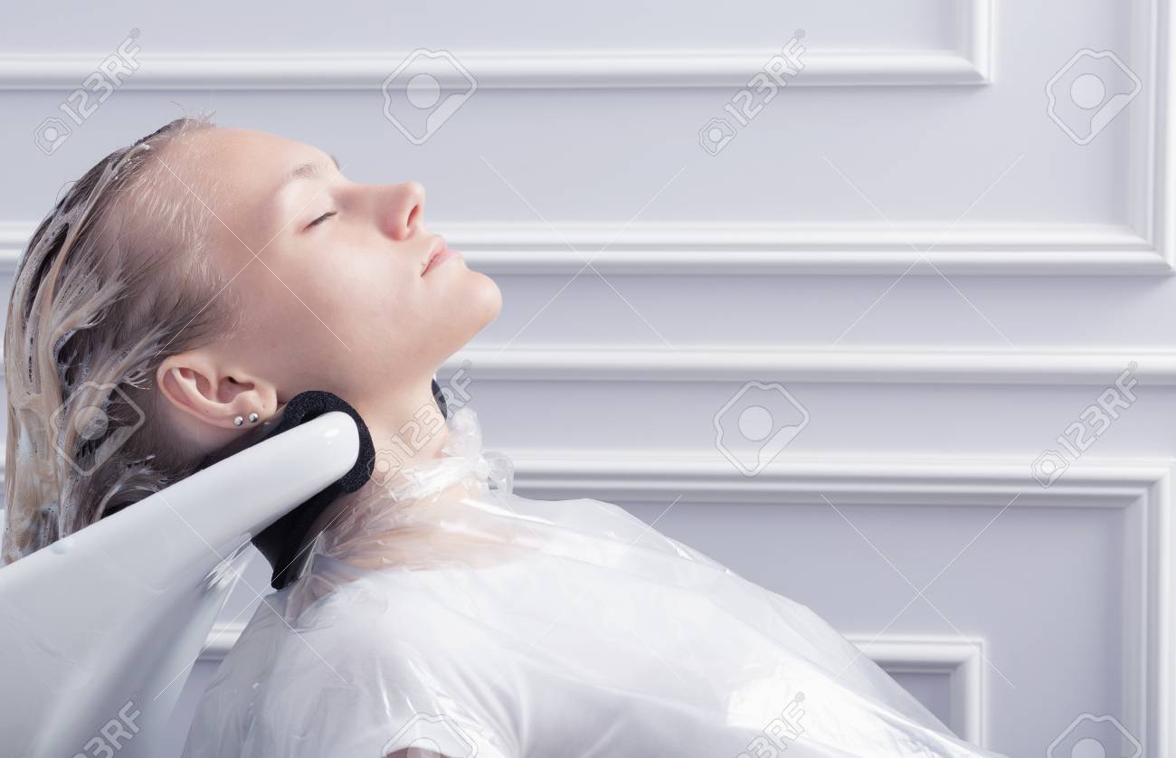 A blonde woman washing hair in hairdressing salon after hair coloring - 66820327 A blonde woman washing hair in hairdressing salon after hair coloring - 66820327