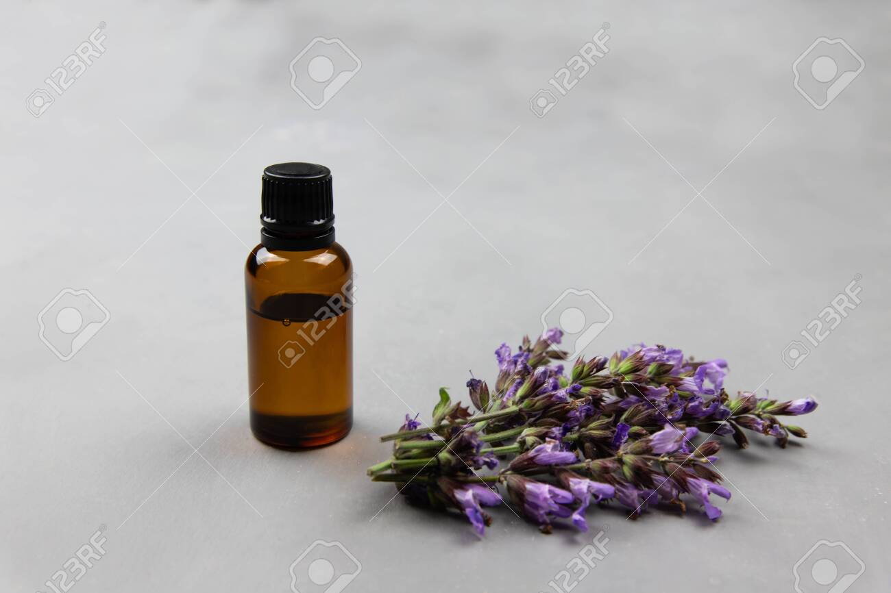 Dark amber glass bottle full of Essential oil and clary sage flowers, salvia sclarea, for aromatherapy. Naturopathy, wildflowers extract fragrance - 147825467 Dark amber glass bottle full of Essential oil and clary sage flowers, salvia sclarea, for aromatherapy. Naturopathy, wildflowers extract fragrance - 147825467