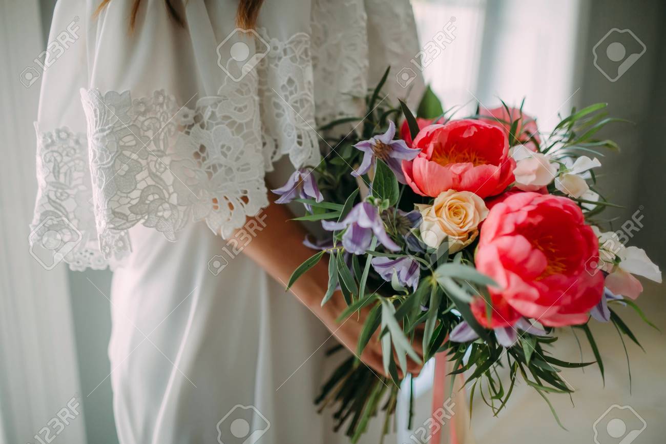 Bride Holds In Hands A Rustic Wedding Bouquet With White Roses And Crimson Peonies On Window Bride Holds In Hands A Rustic Wedding Bouquet With White Roses And Crimson Peonies On Window