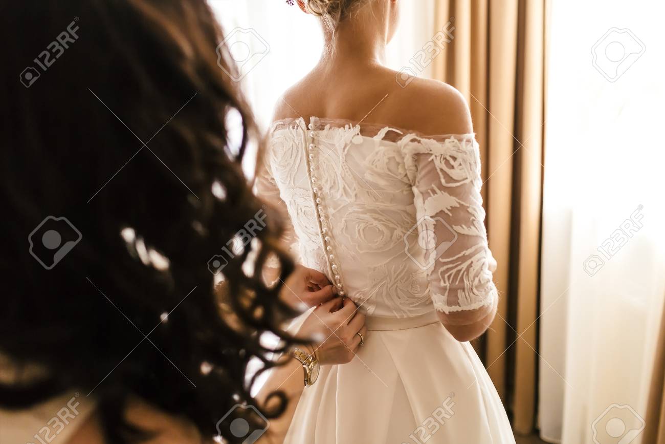 mother helps fasten a wedding dress the bride before the ceremony