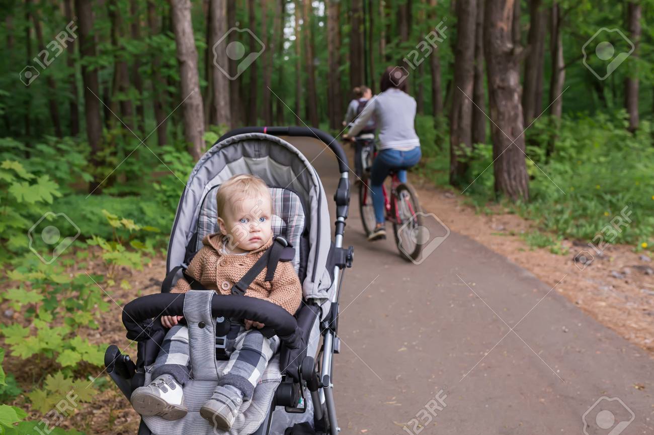 自然に座っているベビーカーの赤ちゃん 愛らしい 1 歳児ベビーカー自転車道に緑夏の森の中を歩く の写真素材 画像素材 Image