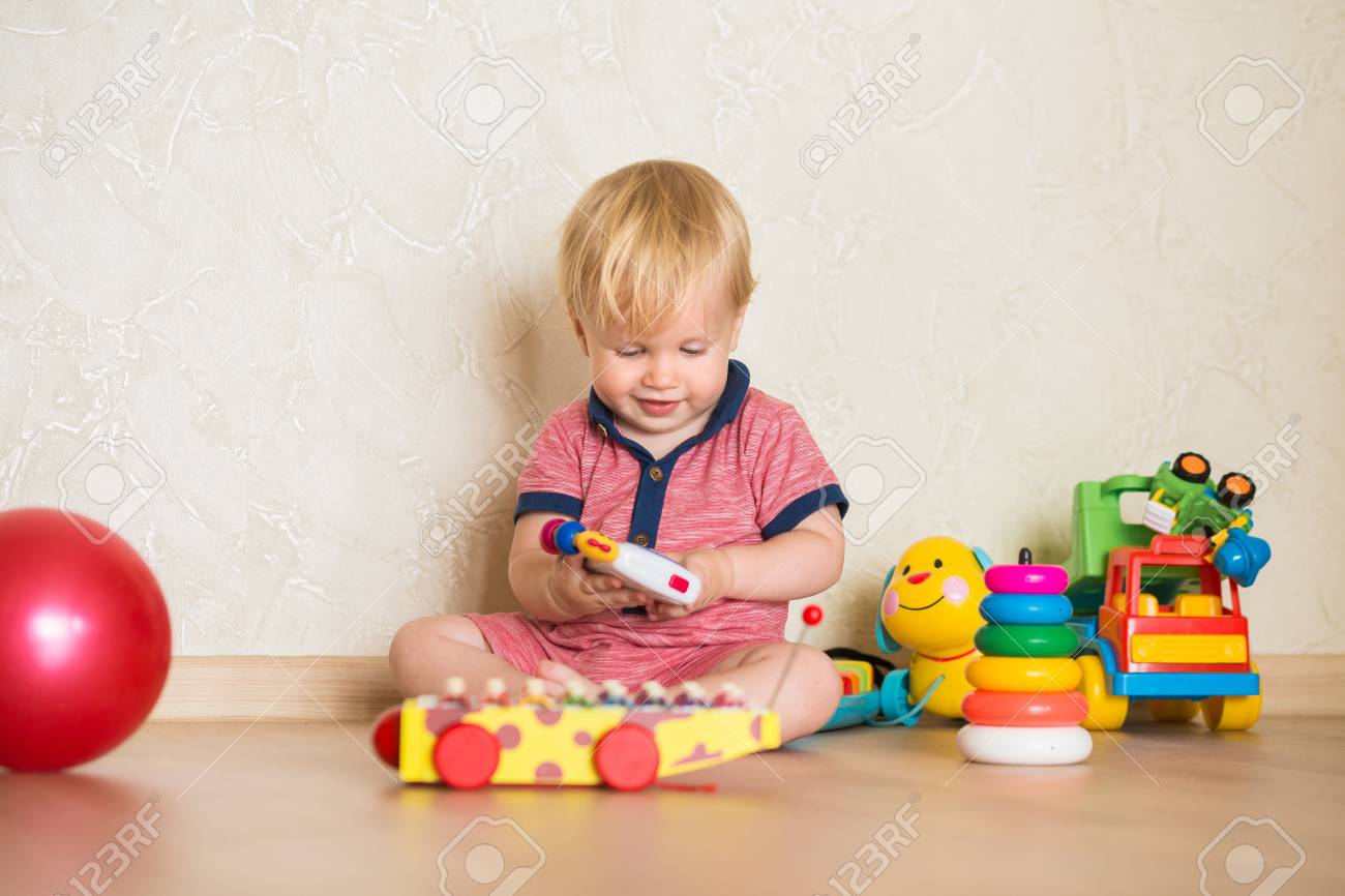 Retrato De Un Hermoso Bebé En El Suelo Con Los Juguetes Retrato De Un Hermoso Bebé En El Suelo Con Los Juguetes