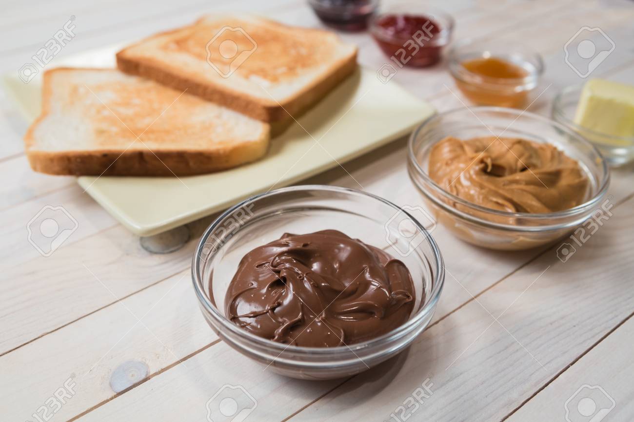 サンドイッチやピーナッツ バター チョコレート ペースト ストロベリー カシス アプリコット ゼリーか白い木製テーブルにジャムとトースト の写真素材 画像素材 Image 68216968