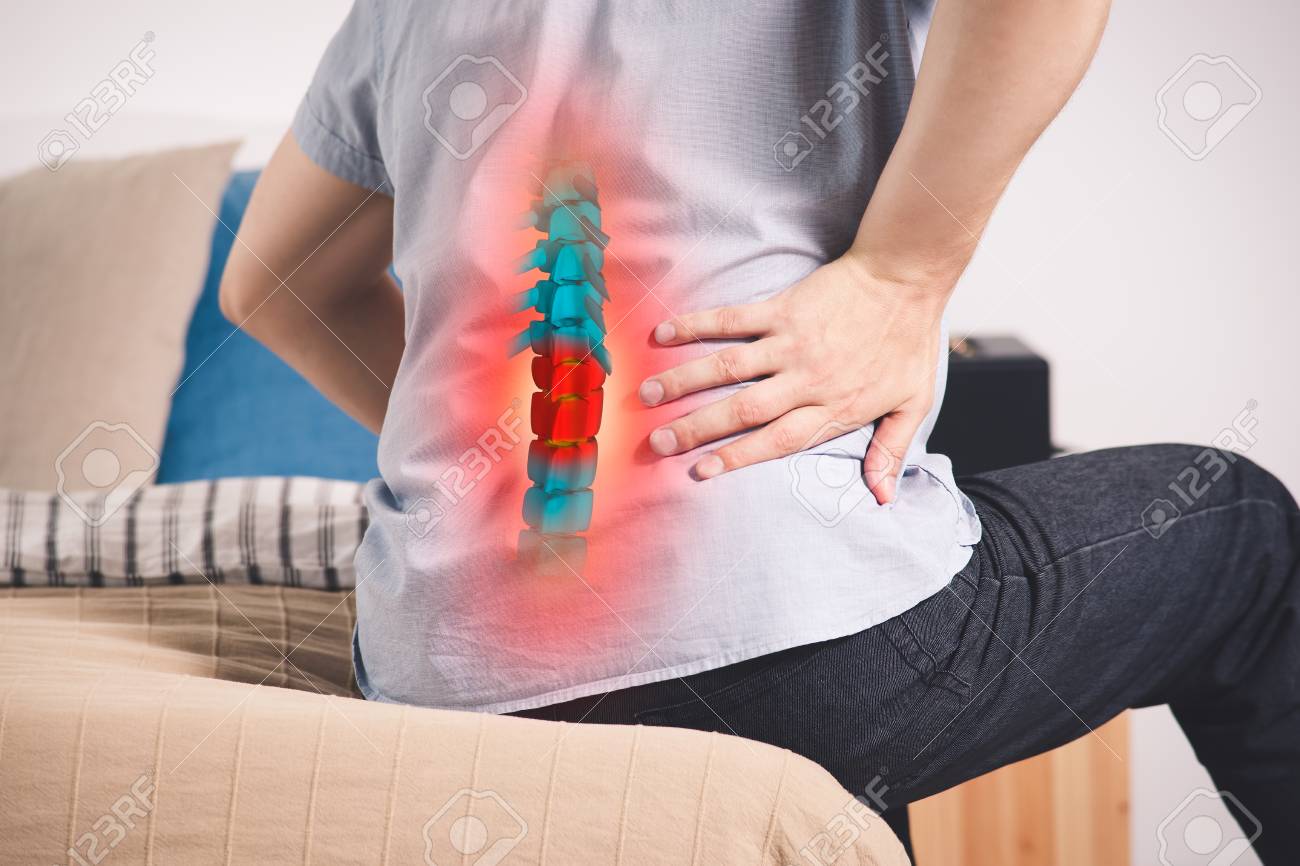 Pain in the spine, a man with backache at home, injury in the lower back, photo with highlighted skeleton - 112153378 Pain in the spine, a man with backache at home, injury in the lower back, photo with highlighted skeleton - 112153378
