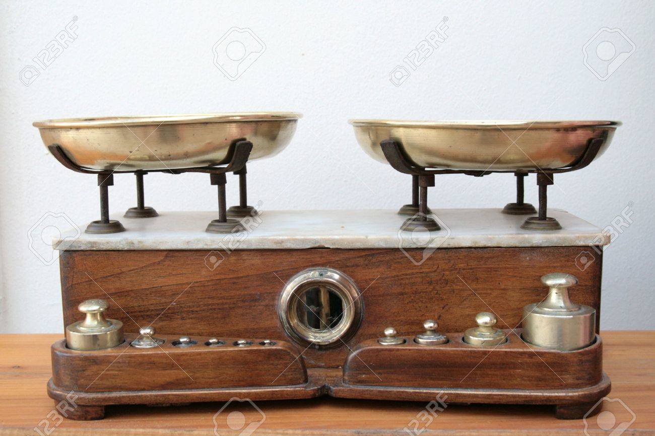 antique scale with brass pans and weights and a wood and marble