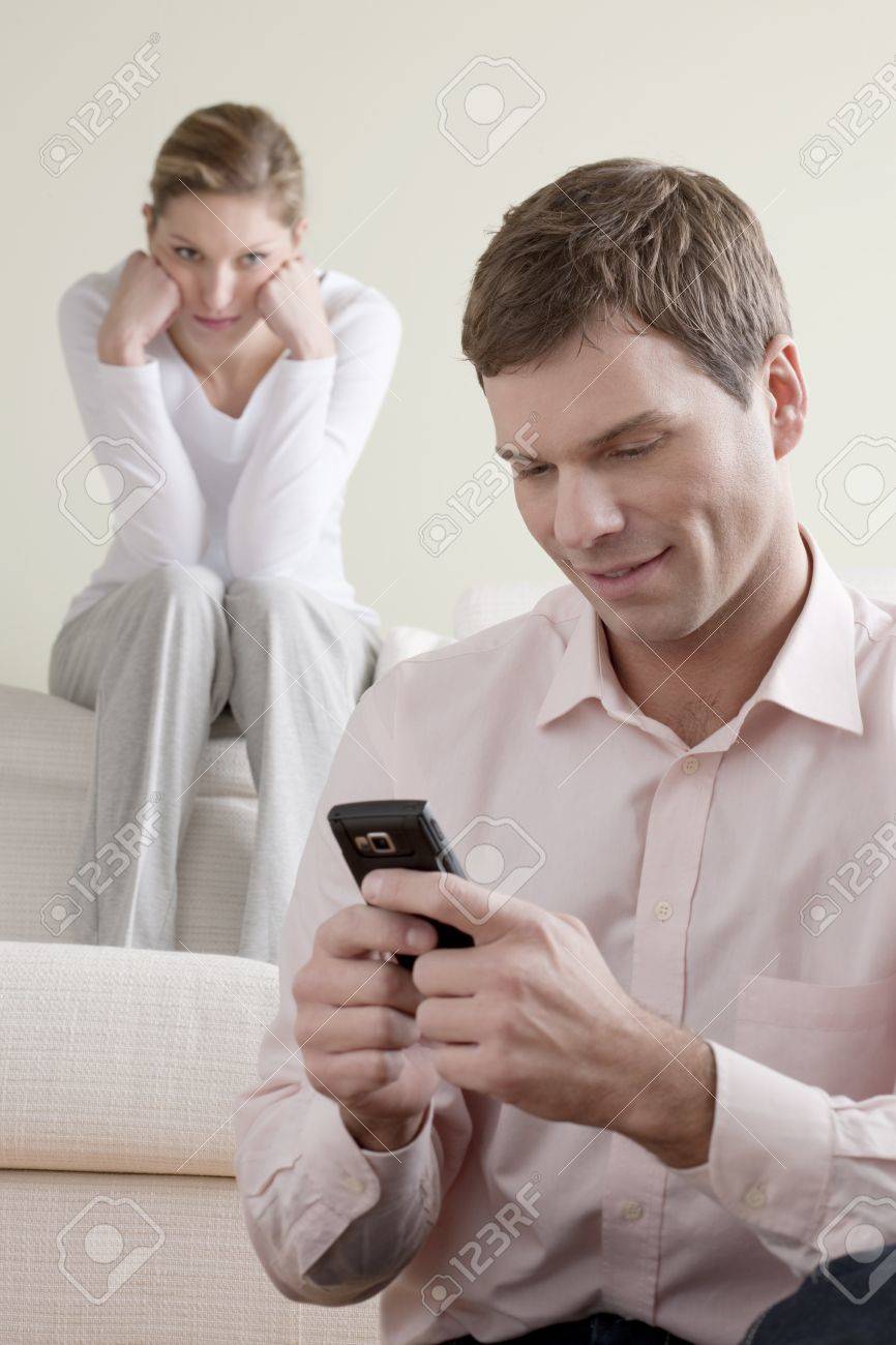 Jealous woman looking at her partner chatting on the phone - 7471226 Jealous woman looking at her partner chatting on the phone - 7471226